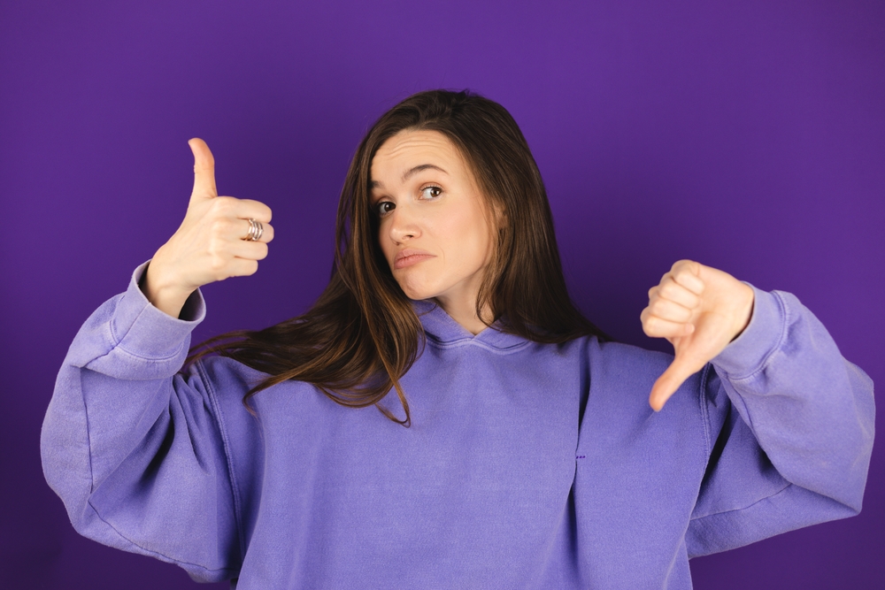 Woman showing thumbs up and down representing mixed signals